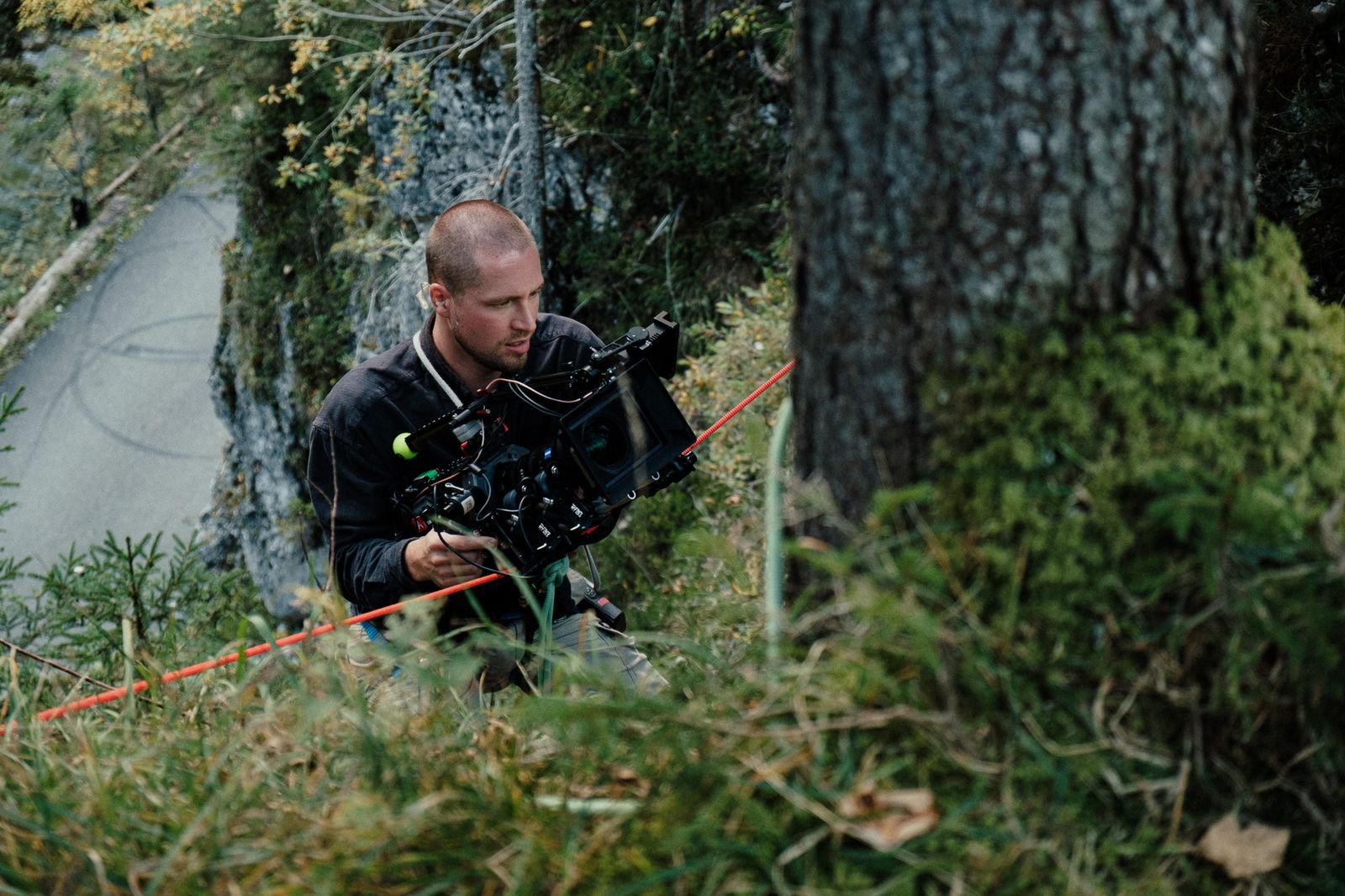 mit kamera im steilen waldhang, gesichert am seil